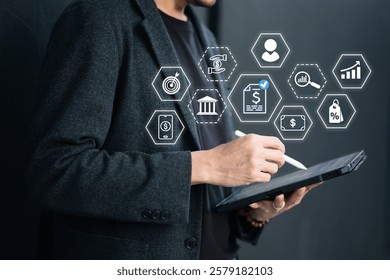 A man is using a digital pen on a tablet with financial and business icons floating around him, symbolizing digital finance, banking and data analysis.