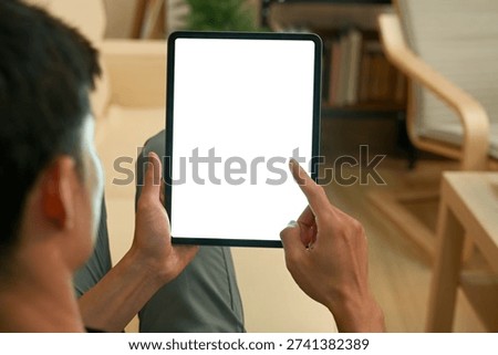 Man using digital tablet blank screen modern design while lying on the sofa in living room.