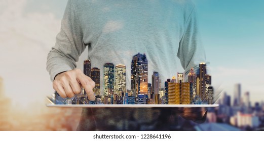 A Man Using Digital Tablet With Modern Buildings Hologram. Real Estate Business And Investment, Smart City And Building Technology