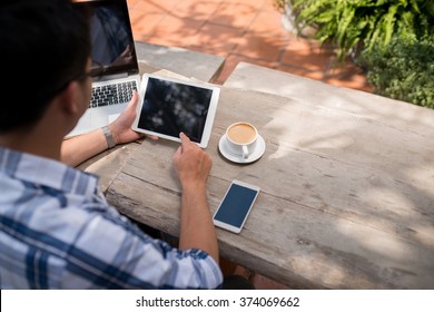 Man Using Digital Tablet In Outdoor Cafe, View Over The Shoulder