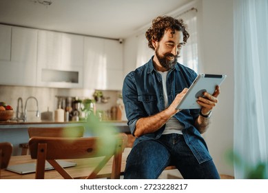 Man using a digital tablet for remote work or online entertainment in his kitchen