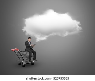 Man using digital tablet and sitting on the shopping cart with white cloud, on gray background, on-line shopping concepts.