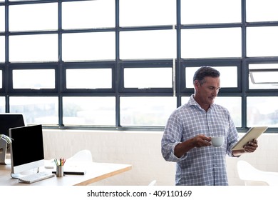 Man using digital tablet while having coffee in office - Powered by Shutterstock