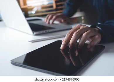 Man using digital tablet, working on laptop computer on office table. Casual business man touching on tablet screen, surfing the internet, online job, freelance at work, close up - Shutterstock ID 2174876903