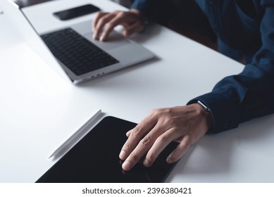 Man using digital tablet, working on laptop computer at office. Business man touching on tablet screen, surfing the internet, online job, smart working, freelnace at work, close up