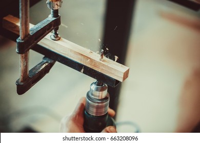 Man Using The Drill Makes A Hole In Wood And Iron Strap. The Process Of Making Desk, Furniture.