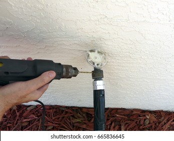 A man is using a drill to remove a backflow preventer device to replace a leaking gasket. The device is sometimes required to protect water supplies.