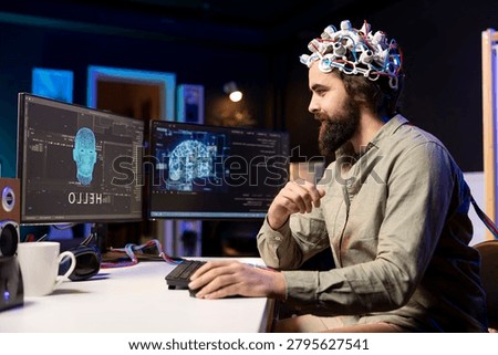 Man using EEG headset to communicate with artificial intelligence on computer in binary code, programmer sending brainwave signals to AI entity on PC using high-tech device.
