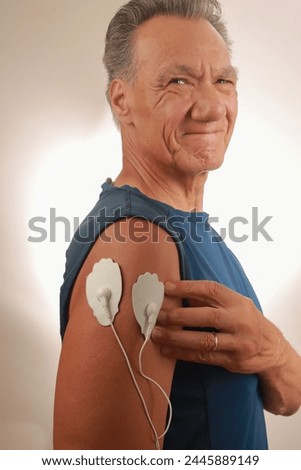 Man using an Electro Therapy Massager or Tens Unit on his Deltoid for pain relief for Muscles and Joints