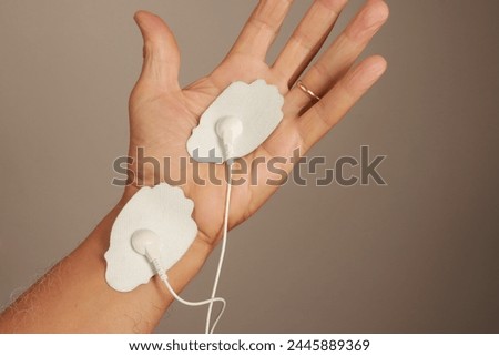 Man using an Electro Therapy Massager or Tens Unit on his hand for pain relief for Carpal Tunnel
 
