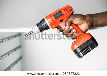 Man using electronic drill install cabinet