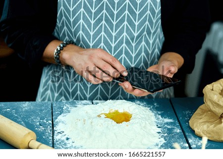 Man using electronic tablet pc in kitchen for baking. Man searching for food recipe in tablet computer. Close up man touching tablet screen and browsing recipes.