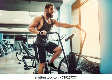 Man using exercise bike at the gym. Fitness male using air bike for cardio workout at Functional training gym. - Powered by Shutterstock