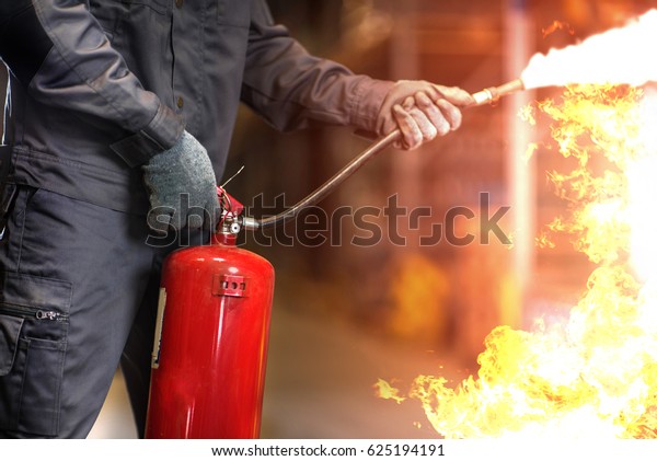 Man\
using fire extinguisher fighting fire closeup\
photo.