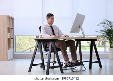 Man using footrest while working on computer in office - Shutterstock ID 1990715432