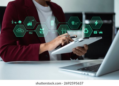 Man using futuristic interface with smart tech and mobile to manage ESG, clean energy, and sustainability data.	