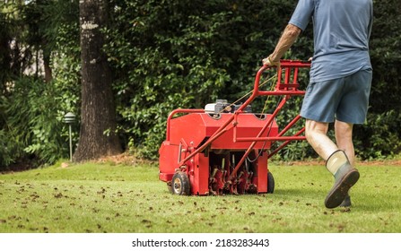 Man using gas powered aerating machine to aerate residential grass yard. Groundskeeper using lawn aeration equipment for turf maintenance. - Shutterstock ID 2183283443