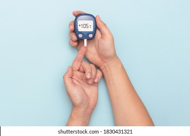 Man using glucometer, checking blood sugar level. Diabetes concept on blue background