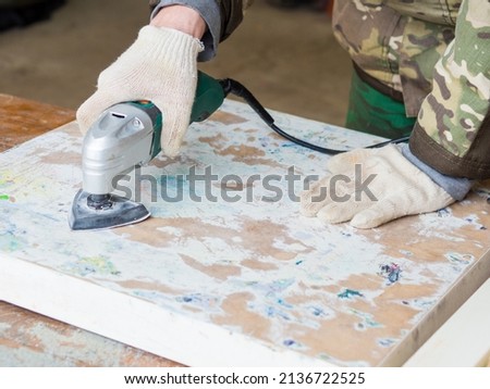 a man using a grinder removes old paint from furniture, restoration of antique furniture. handmade concept