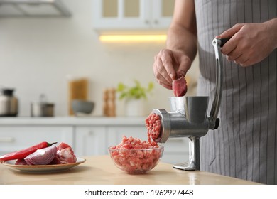 Man using hand meat grinder in kitchen, closeup