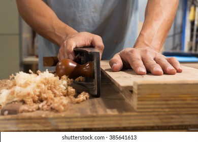 Man Using Hand Plane In Workshop 