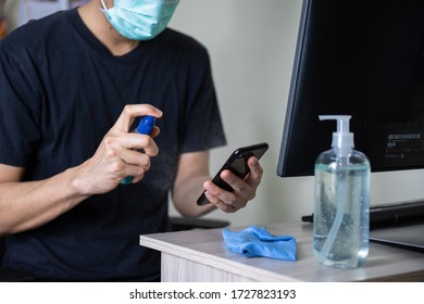 Man Using Hand Sanitizer Gel, Alcohol Spray Clean Surface And Mobile Phone For Prevention Coronavirus, Covid-19 During Work From Home