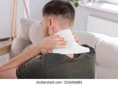 Man Using Heating Pad At Home, Back View