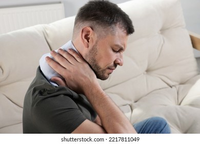 Man using heating pad on sofa at home