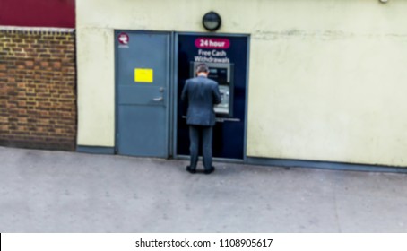 Man Using His Credit Card In An Atm For Cash Withdrawal. Blurred View.