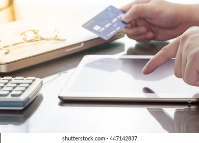 Man nutzt seine digitale Tablette und hält dabei eine Kreditkarte, die zum Online-Shopping gedacht ist, Konzept mit digitalem Business oder E-Commerce Konzept. Nahaufnahme, warmer Ton.