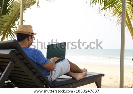 A man using his laptop and working from sea beach, during this pandemic where work from home is part of life , now people can work from anywhere and at the same time have a feel of vacation. 