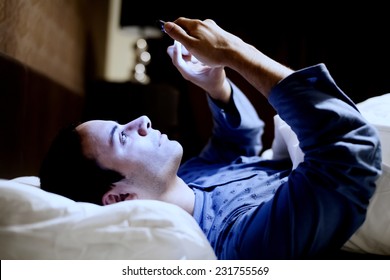 Man Using His Mobile Phone In The Bed