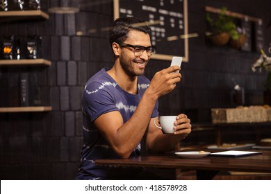 Man using his smartphone and drinking coffee in a coffee shop - Powered by Shutterstock