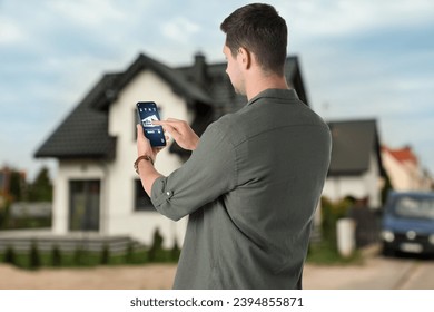 Man using home security system application on smartphone outdoors