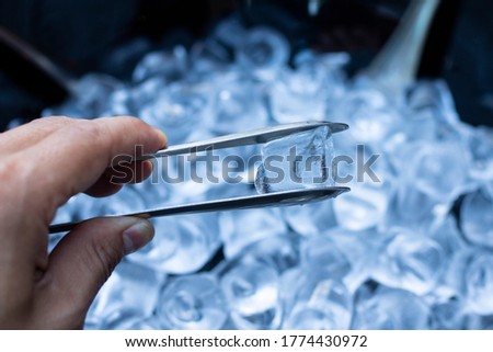 Man using ice clip. Ice cubes Close Up.