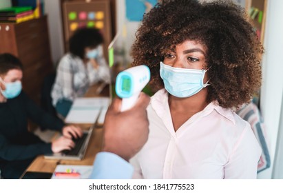 Man using infrared forehead thermometer for checking body temperature of workers - Focus on woman's right eye - Powered by Shutterstock