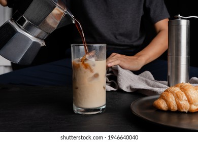 Man Using Italian Classic Moka Coffee Pot Pouring, Coffee Make Cold Of Iced Coffee In A Glass And Croissant Grinder Equipment Tool Brewing Table. 