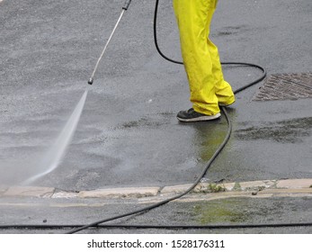 Man Using Jet Power Washer Hose To Clean Paint Off Road Surface. Road Cleaning With High Power Pressure Water Jet Hose