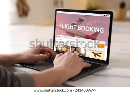 Man using laptop to book flight at white table, closeup
