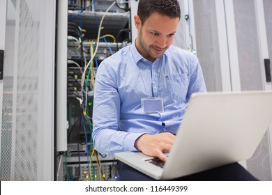 Man using laptop to check servers in data center