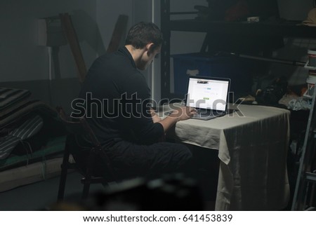 Man using laptop in dark room.