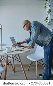 Man using laptop and notebook while leaning during remote work