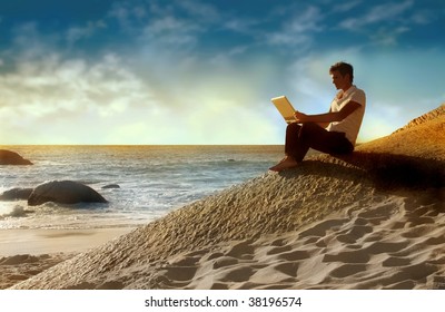 Man Using Laptop On The Beach At The Sunset