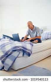 Man using laptop on bed