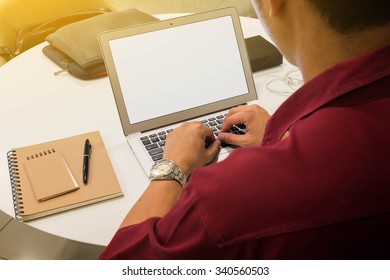 Man using laptop on table with note book and pen
