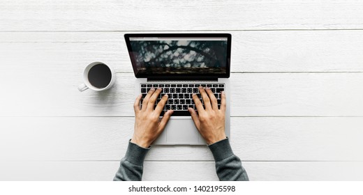 Man Using A Laptop On  A Wooden Table Aerial View