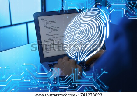 Man using laptop at table in dark room, closeup. Criminal offence