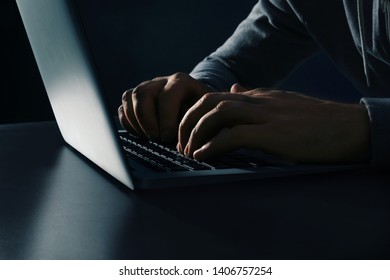 Man Using Laptop At Table On Dark Background, Closeup. Criminal Activity