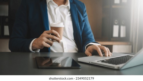 man using laptop and typing on laptop and holding coffee cup in cafe, home office in morning light
 - Powered by Shutterstock