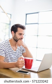 Man using laptop while having coffee at home. Working from home in quarantine lockdown. Social distancing Self Isolation
